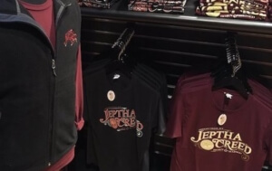 A mannequin wearing a vest and shirt, with other shirts on display.