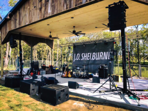 outdoor stage setup for a musical performance by an artist or band named J.D. Shelburne