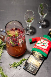 holiday-themed batch cocktail, likely a cranberry and rosemary-infused vodka drink,