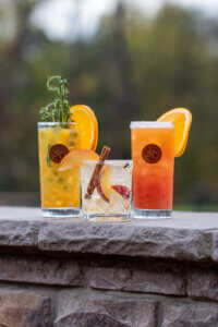 Three cocktails on a stone ledge.