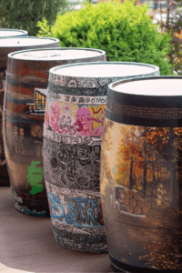 A row of graffiti-covered barrels in an urban setting.