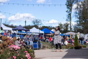 Photo of Jeptha Creed Fall Harvest Festival with Singer on Stage, Crowd Watching, and Booths in the background
